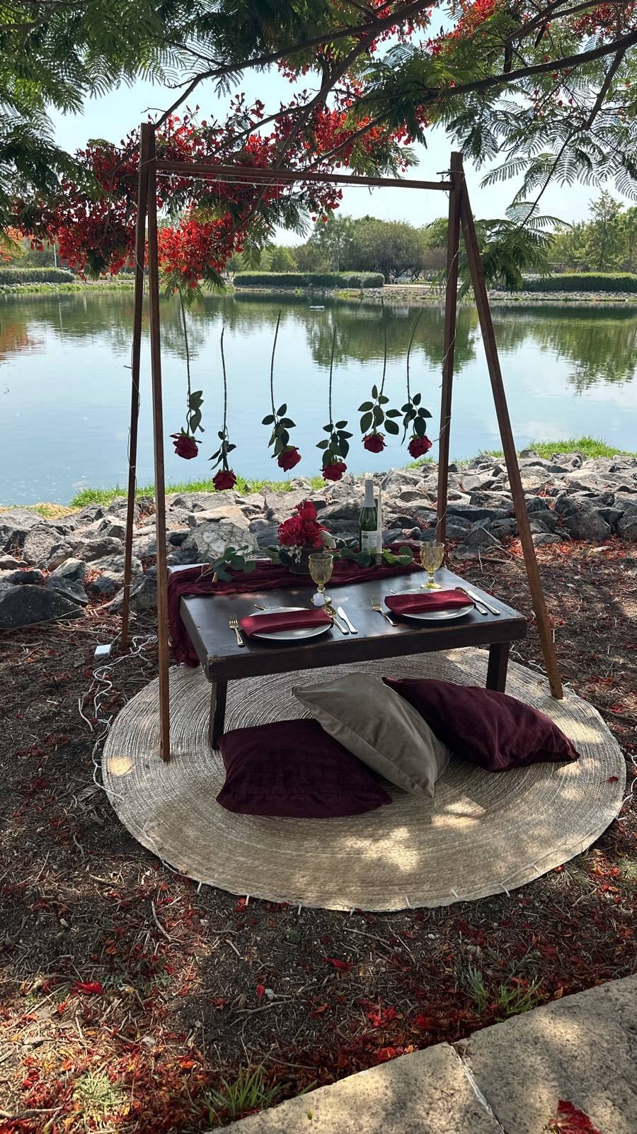 Picnic de lujo con manta y rosas junto al lago al atardecer